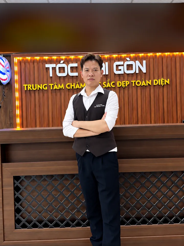 Cảnh Phong, quản lý TÓC SÀI GÒN, đứng khoanh tay trước quầy lễ tân