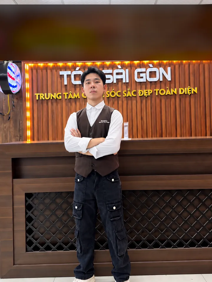 Hoàng Tùng, chuyên gia tạo mẫu tóc, đứng khoanh tay trước quầy lễ tân