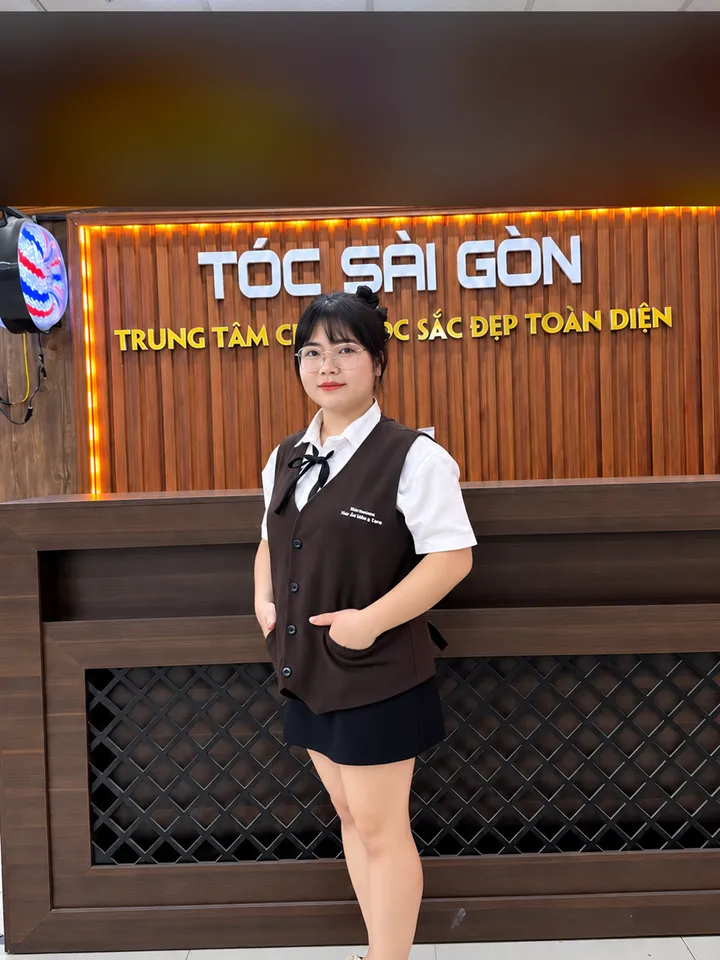 Ly Ly, kỹ thuật viên gội đầu, đứng trước quầy lễ tân