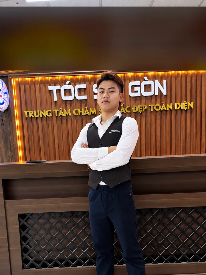 Phát Alo, chuyên gia tạo mẫu tóc, đứng khoanh tay trước quầy lễ tân