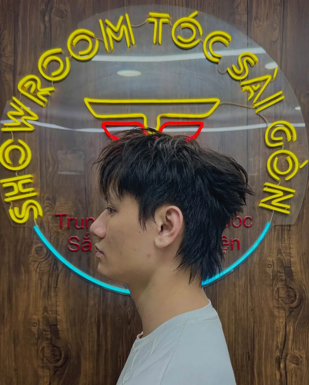 Kiểu tóc mullet nhìn nghiêng trước bảng neon của tiệm