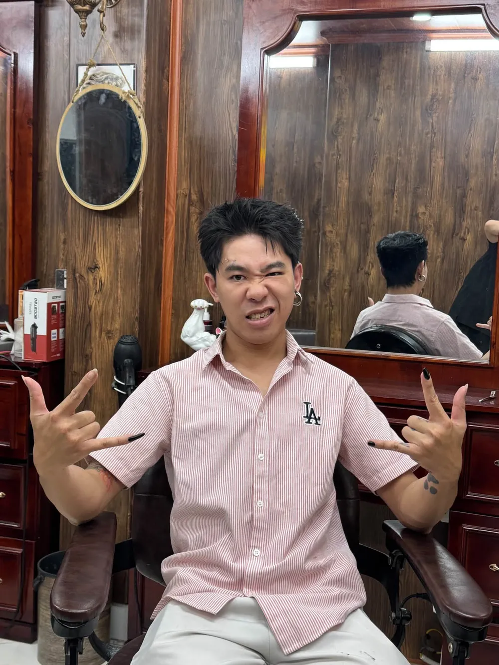 Khách ngồi ghế barber giơ hai tay sau khi cắt tóc
